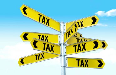 Sign pointing in many directions stating tax