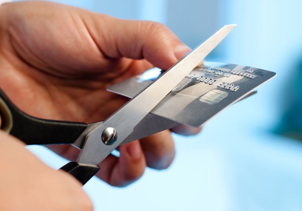 person cutting a credit card with scissors