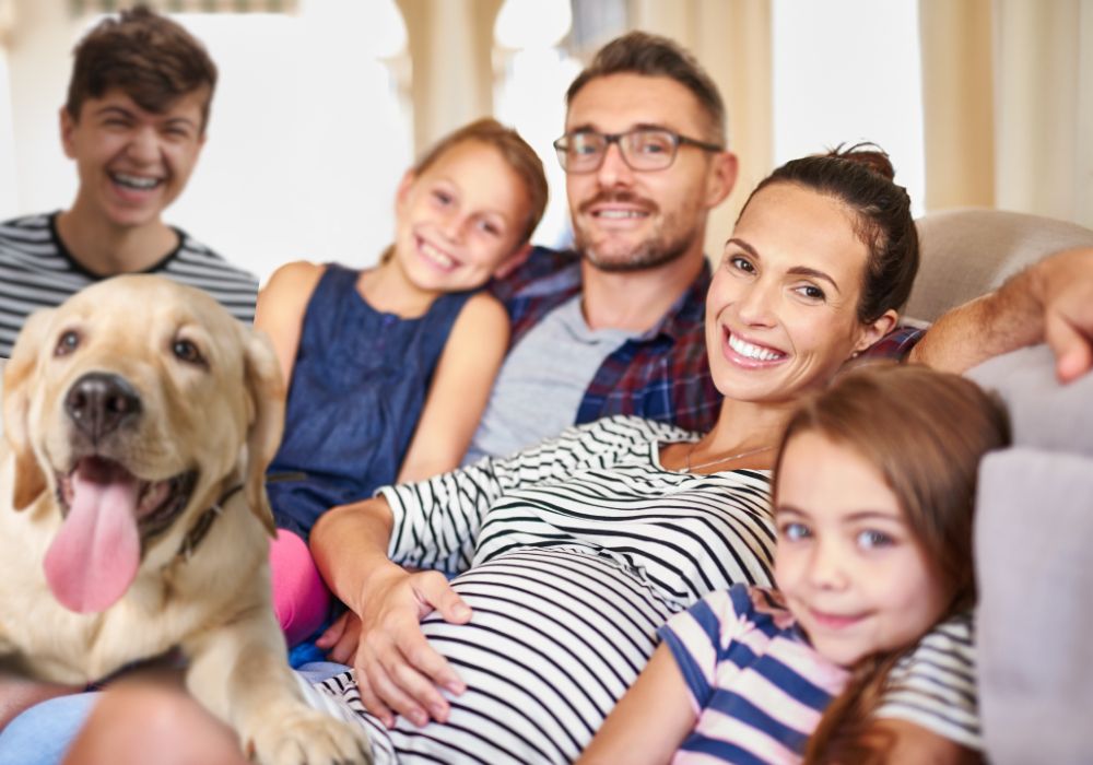 family of five and their labrador dog on a couch and the mum is pregnant