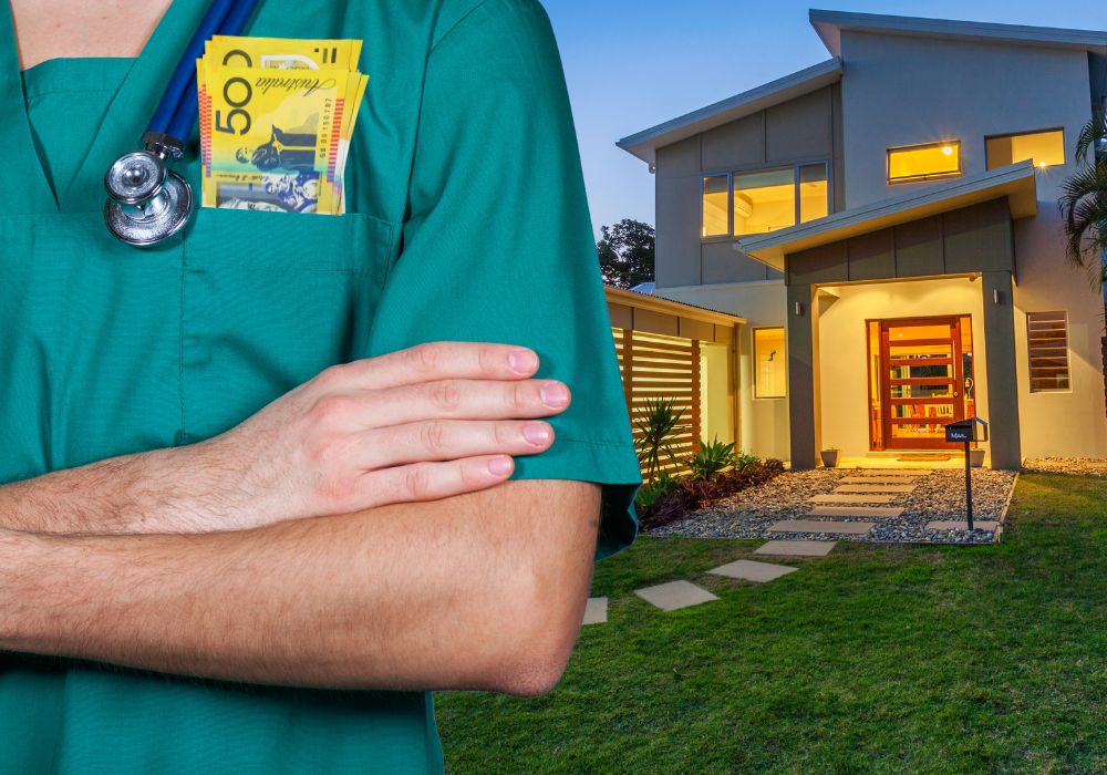 A doctor in green scrubs standing out the front of a modern australian home with $50 notes in his pocket and a stethoscope around his neck.