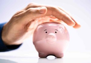 a piggy bank being protected by a hand