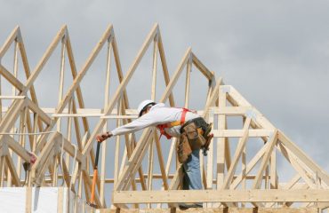 Male builder in his safety gear on a truss roof that is being built