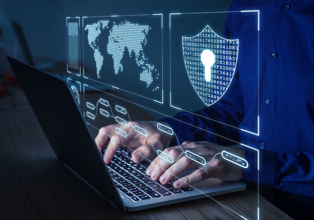 Man in blue button up shirt typing on a laptop computer with graphics of cyber security signs and a world map.