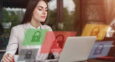 Woman at a desk in front of a laptop with graphic locks floating around her suggesting data security.