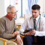 Young doctor speaking to a doctor in his late 60's about a treatment over an ipad.