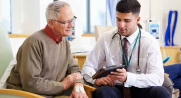 Young doctor speaking to a doctor in his late 60's about a treatment over an ipad.